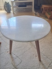Table basse ronde en marbre, avec des pieds en bois clair. Très bon état global.